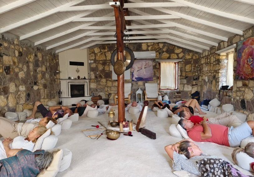 Taş duvarlı bir salonda uzanan katılımcılarla grup ses meditasyonu